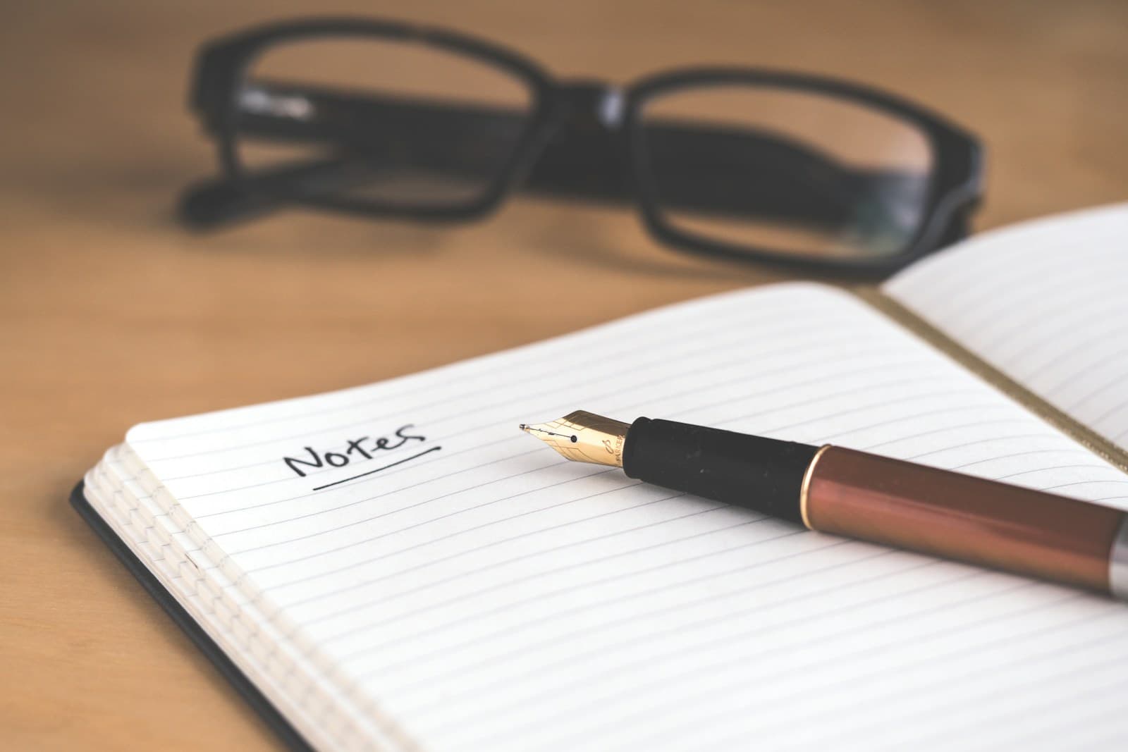 Open notebook with pen beside a laptop on a desk